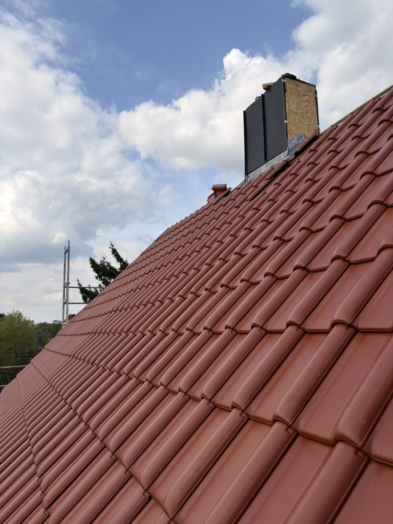Fertige Dach-Neueindeckung mit Tondachziegeln und verkleidetem Schornstein durch die Walter Bau UG