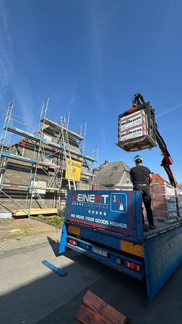 Anlieferung von Dachziegeln per Kran auf einer Baustelle der Walter Bau UG